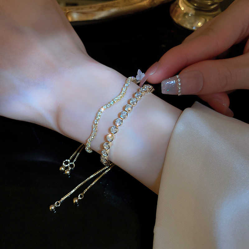 Close-up of a wrist wearing gold bracelets with a hand adjusting them.