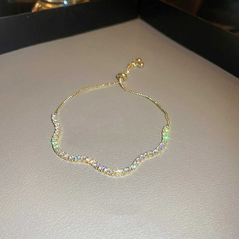 Gold bracelet on a light gray surface
