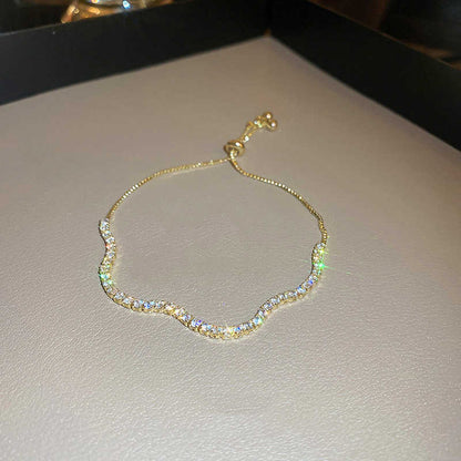 Gold bracelet on a light gray surface