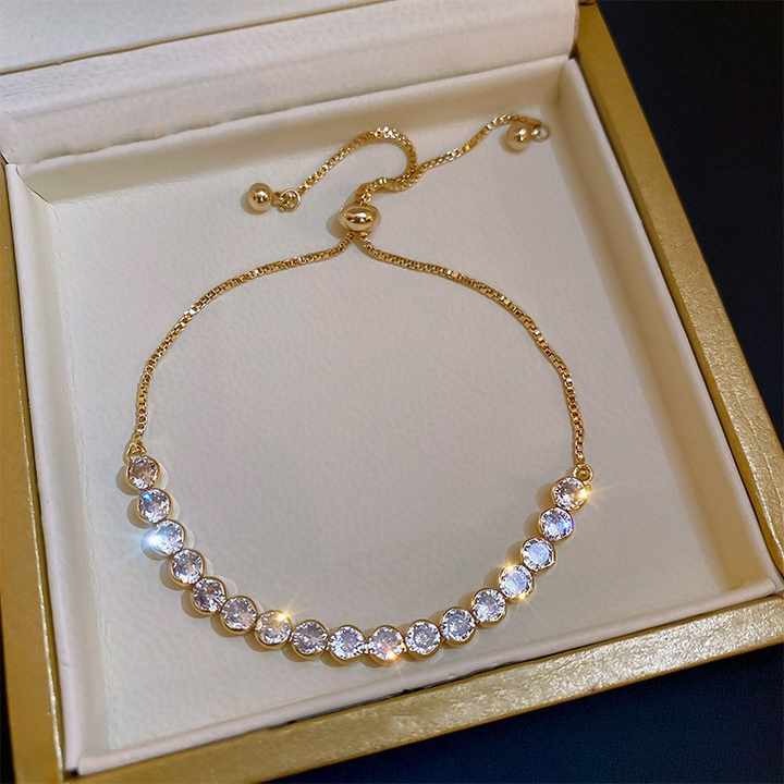 Gold bracelet with crystals on a white cushion in a gold box