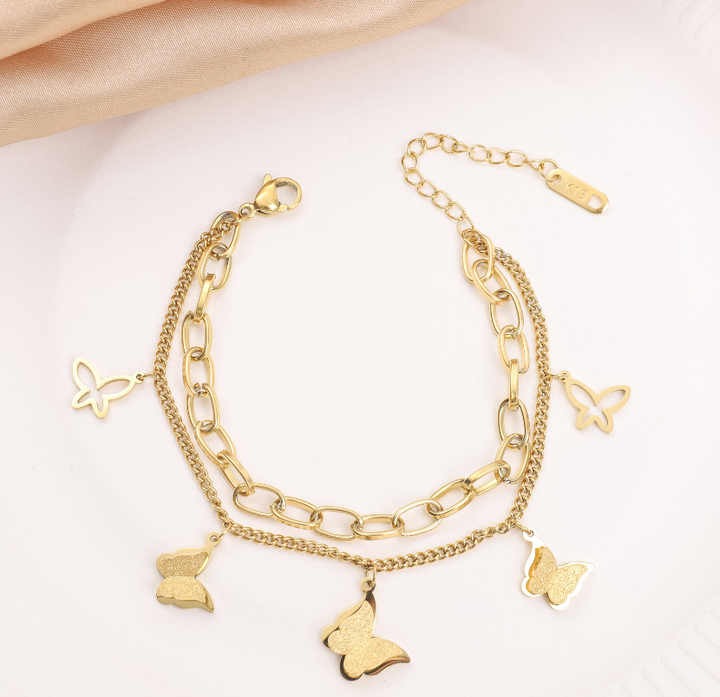Gold butterfly charm double chain bracelet on white background