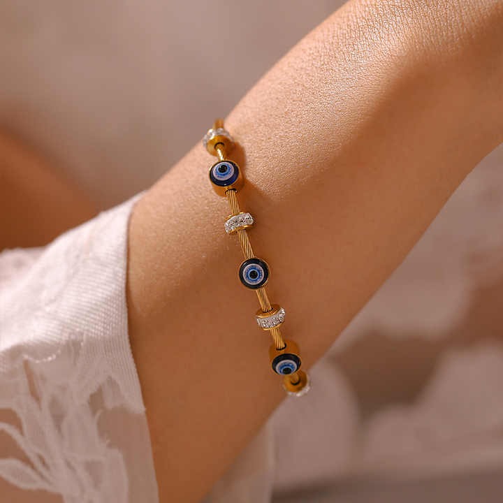 Model’s wrist adorned with a gold evil eye cable bangle with elegant sparkle and symbolic protection.