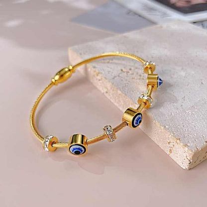 Gold bracelet with evil eye beads on a textured stone.