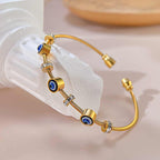 Angled view of an evil eye gold bangle resting on a glass jar, highlighting its sparkle and finish.