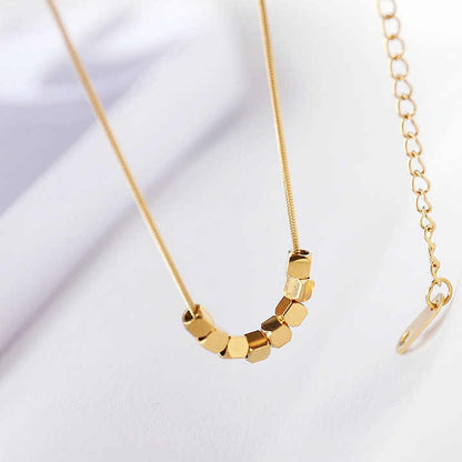 Gold necklace with geometric pendant on a light background