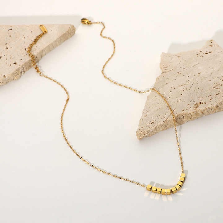 Full gold bead necklace styled with stone props on flatlay