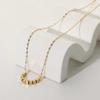 Minimalist pixel chain necklace draped over white decorative curve