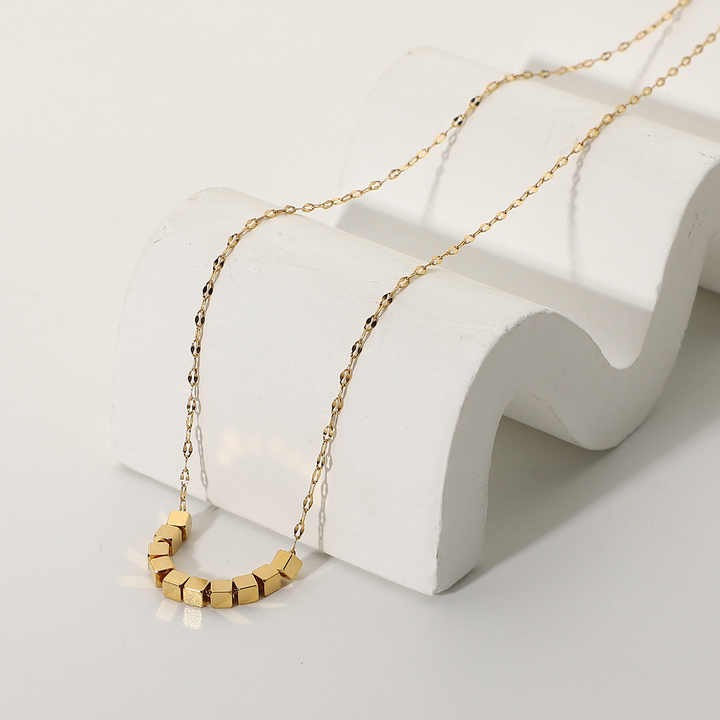 Minimalist pixel chain necklace draped over white decorative curve