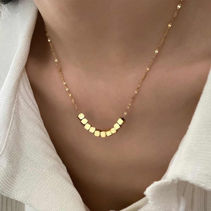 Pixel Necklace with hexagonal gold beads styled on white shirt