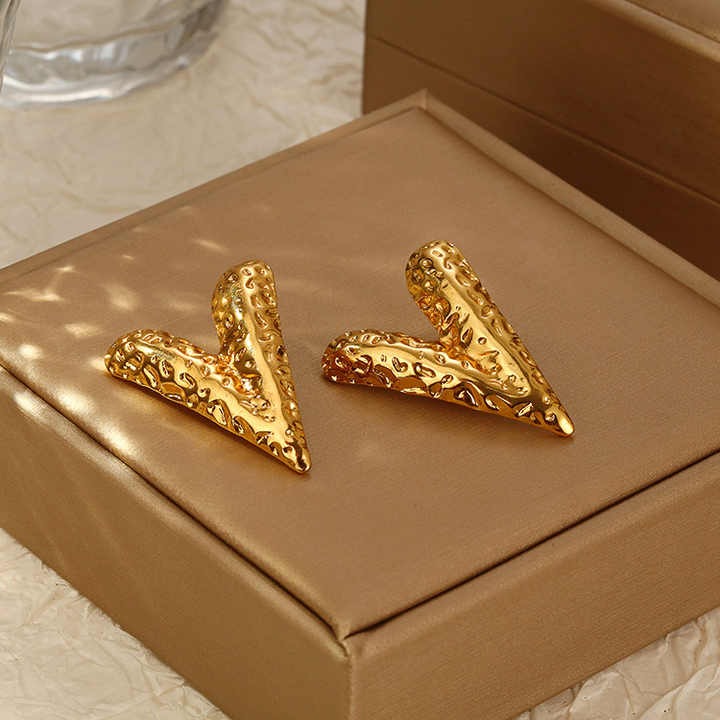 Sculpted gold V earrings displayed elegantly on a Brown jewelry box, highlighting their statement-making shine and texture.