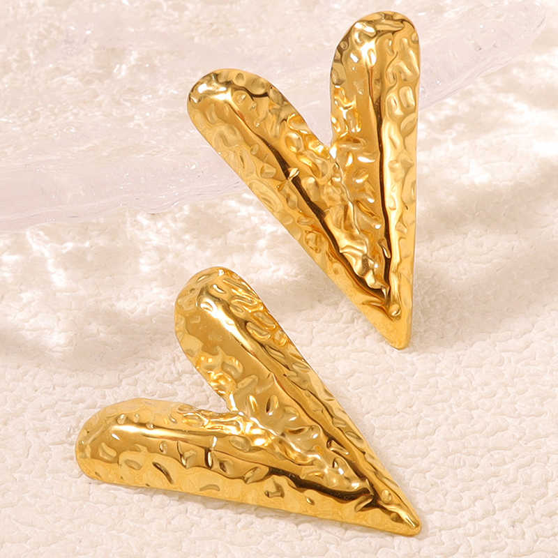 Close-up of Textured V Earrings showcasing the hammered gold finish and pointed V silhouette on a textured ivory surface