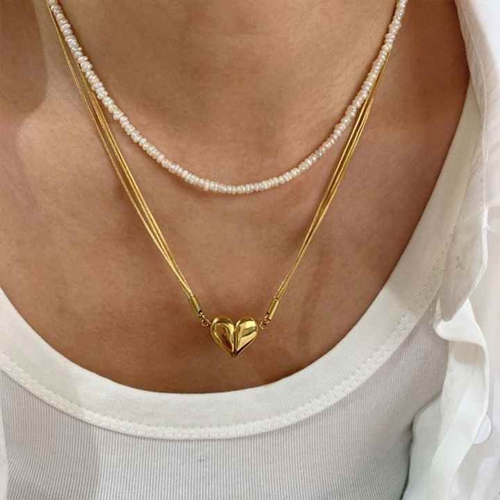 Layered look with pearl necklace and gold heart pendant on neck