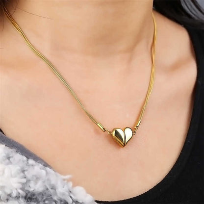 Model wearing glossy gold heart necklace on neckline