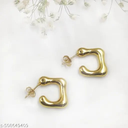 Gold C-shaped earrings on a flat white background with delicate dried flowers.