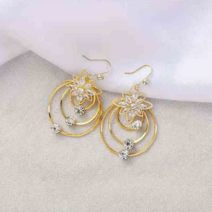 Close-up of gold-plated lotus tassel earrings on white background