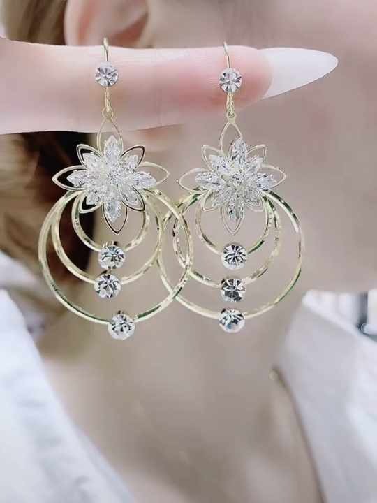 Gold earrings with floral design and dangling tassels, sparkle in light