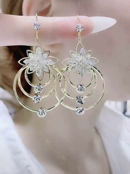 Gold earrings with floral design and dangling tassels, sparkle in light