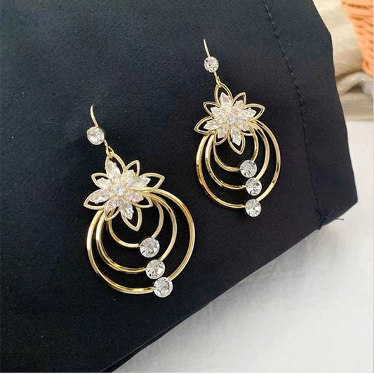 Lotus-shaped earrings with hanging crystals, displayed against fabric
