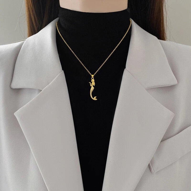 Model styling gold mermaid chain over black top and white blazer