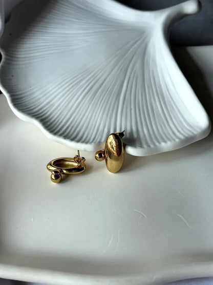 Side view of Pebble Earrings on a textured dish, showing earring post and curvature