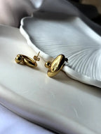 Angled close-up of Pebble Earrings highlighting reflective surface and polished gold design