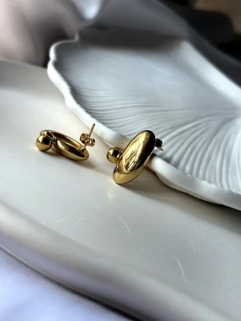 Angled close-up of Pebble Earrings highlighting reflective surface and polished gold design