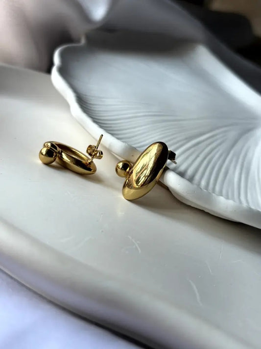 Angled close-up of Pebble Earrings highlighting reflective surface and polished gold design