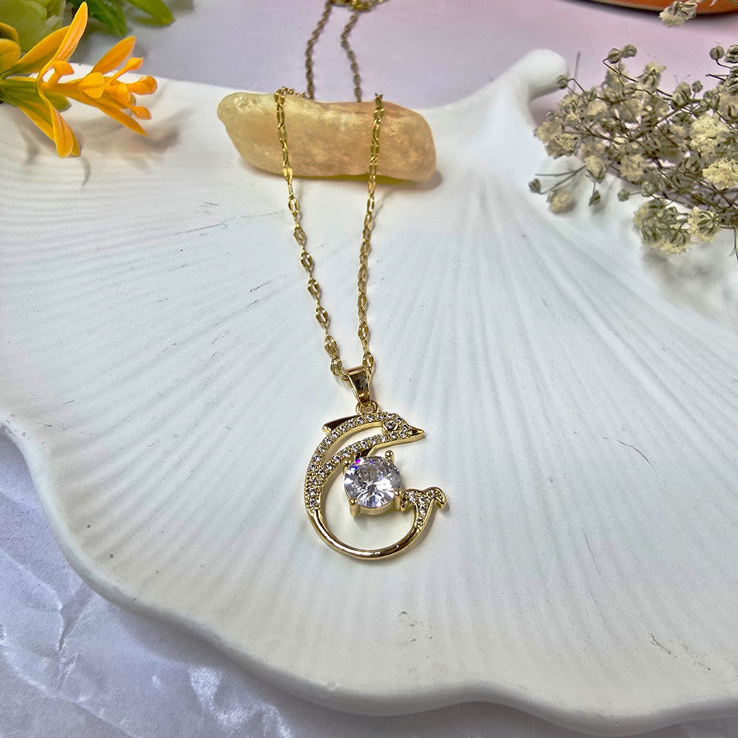 Close-up of Dolphin Pendant Chain on white shell background showcasing crystal-studded pendant.