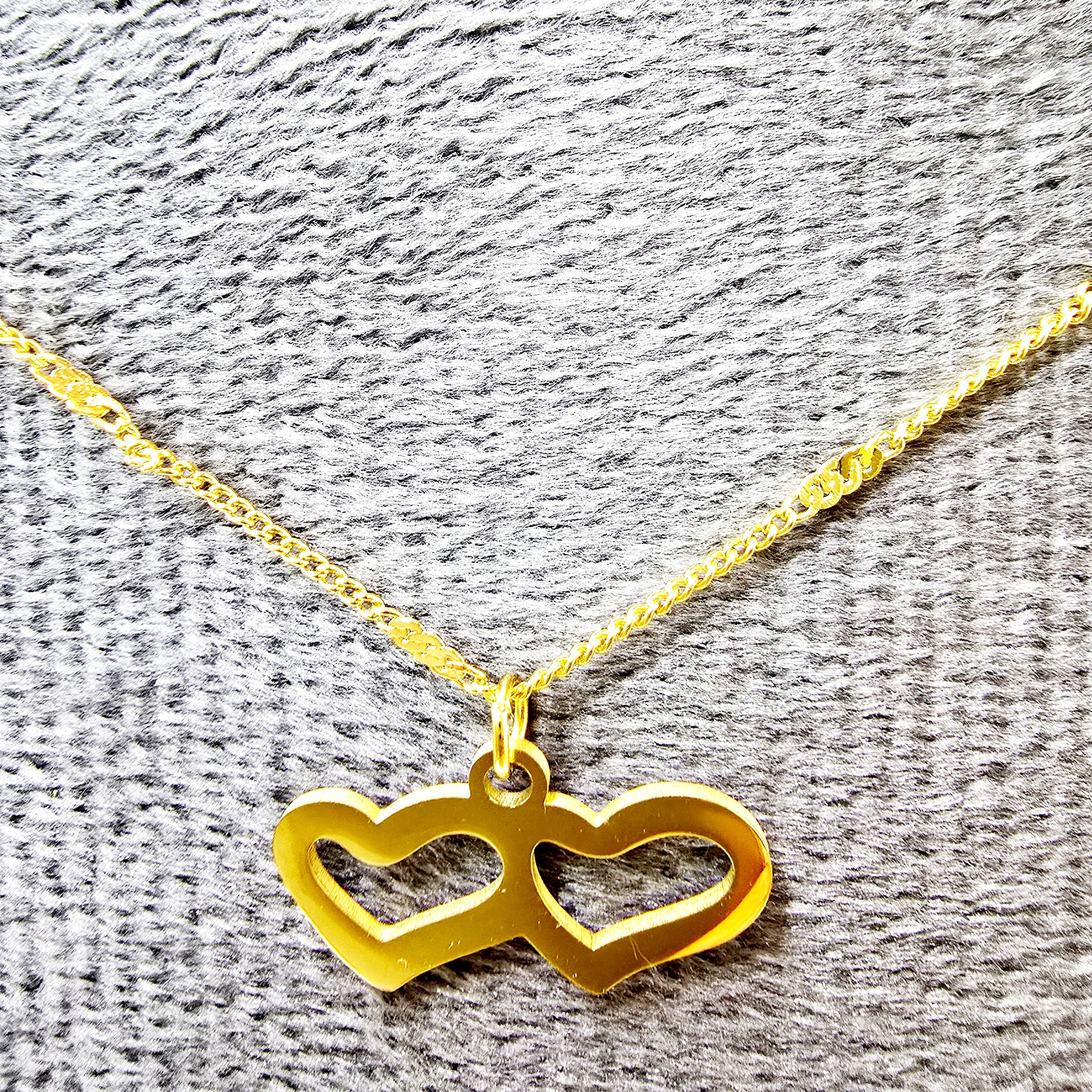 Twin Heart Necklace on grey velvet background showing gold-plated double heart pendant.