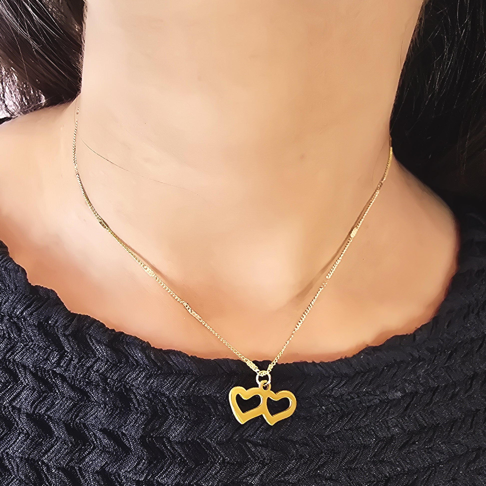 Model wearing Twin Heart Necklace – elegant gold chain with interlocked hearts pendant.
