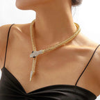 Woman wearing gold-tone serpent necklace with crystal snakehead – closeup on neckline.