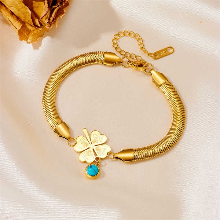 Elegant gold charm bracelet with turquoise evil eye charm on satin background