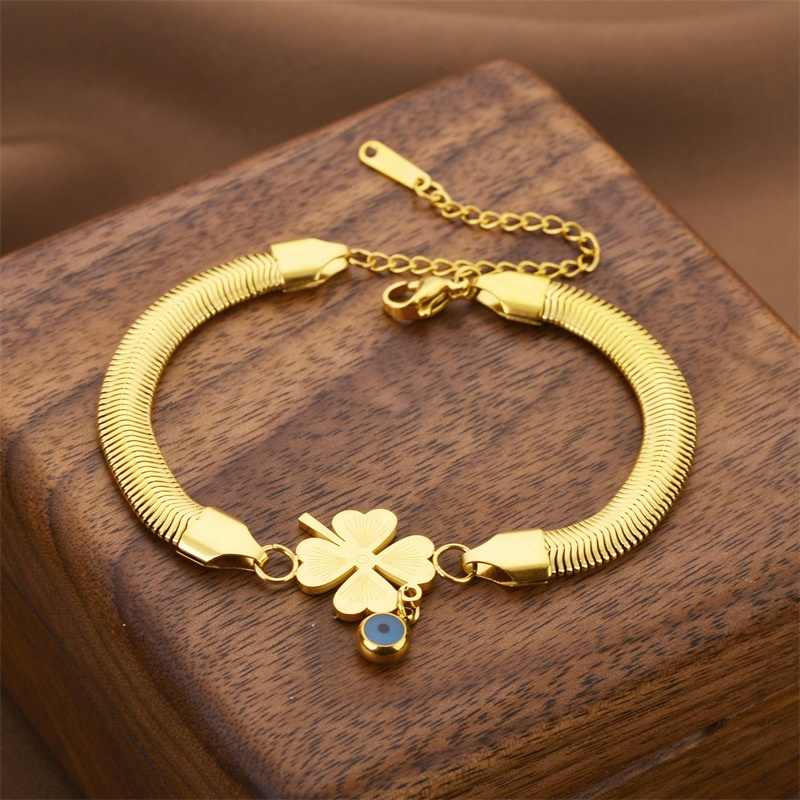 Adjustable gold bracelet with clover and blue evil eye on wooden display