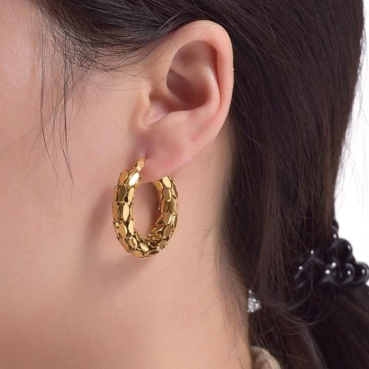 Close-up of snake scale hoop earrings on model’s ear