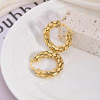Top-down view of snake scale earrings styled on plate