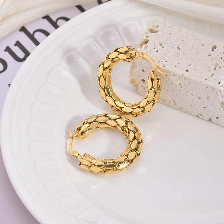 Top-down view of snake scale earrings styled on plate
