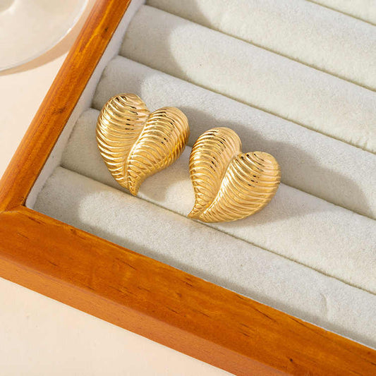 Bold gold striped heart earrings displayed in a cream velvet jewelry tray with a wooden border