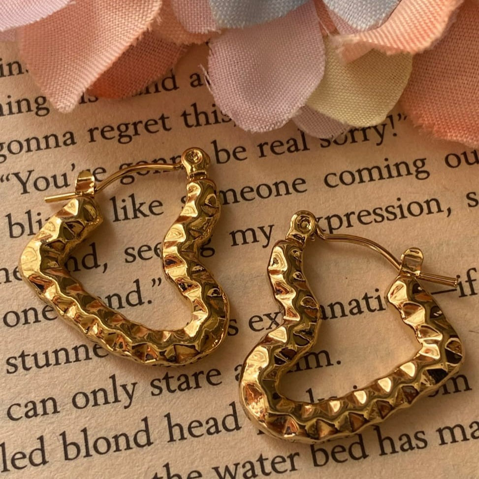 Gold hoop earrings on a piece of text paper with flowers in the background