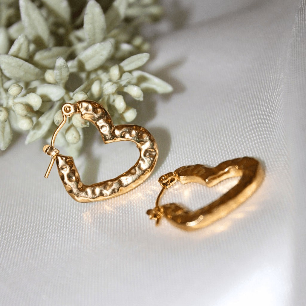  Textured heart earrings on satin with a floral decoration in the background