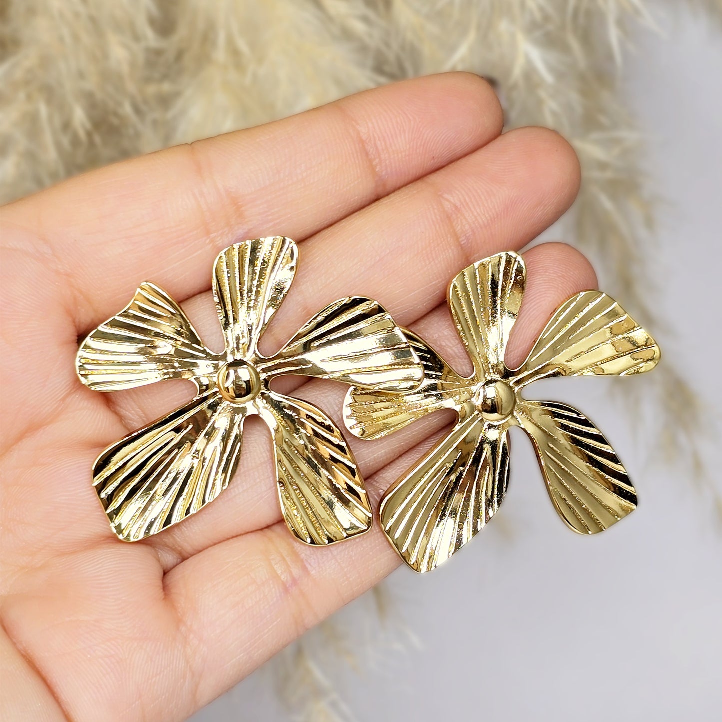 Close-up of gold statement earrings held in hand