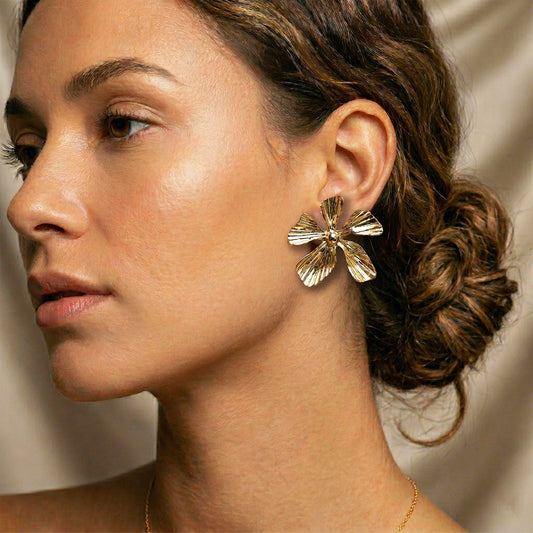 Gold pinwheel statement earrings worn by model close-up