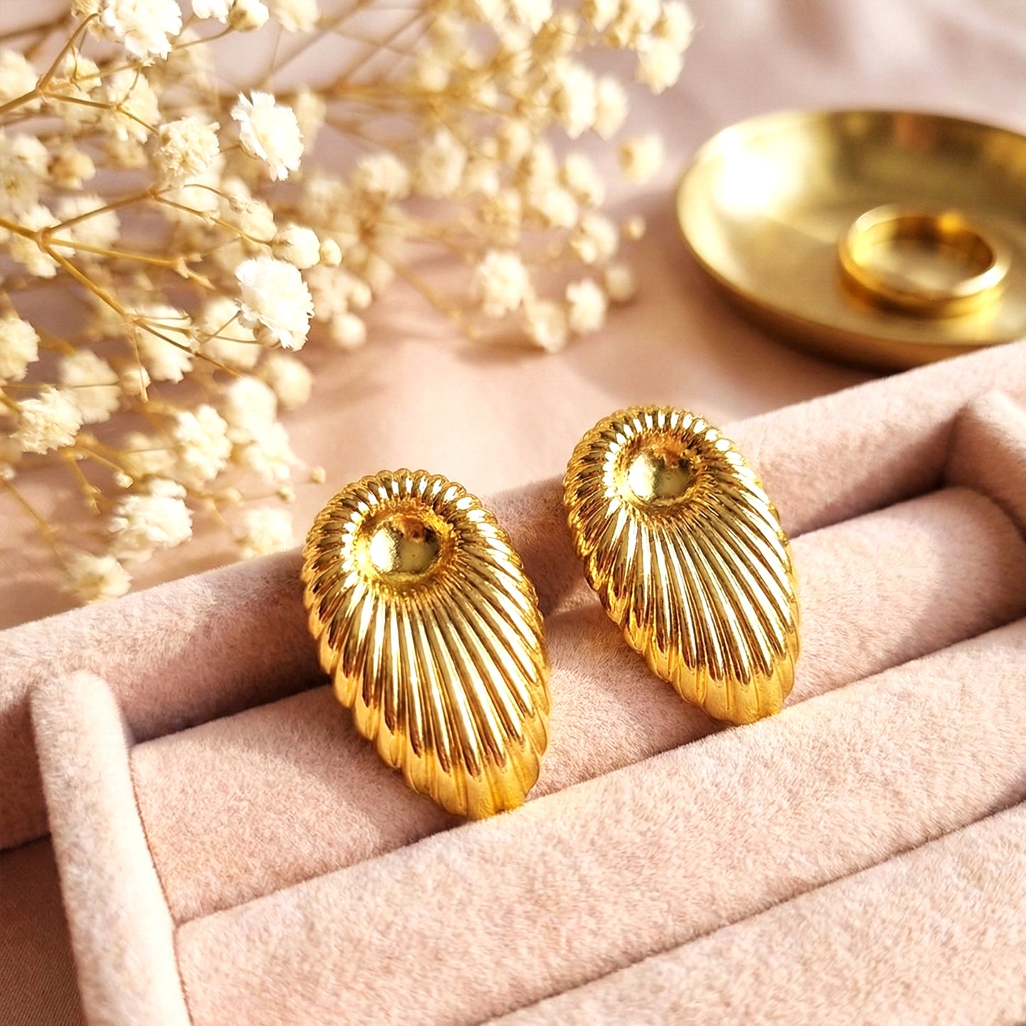 Aesthetic lifestyle shot of the gold shell earrings nestled in a pink velvet jewelry box with dried flowers.