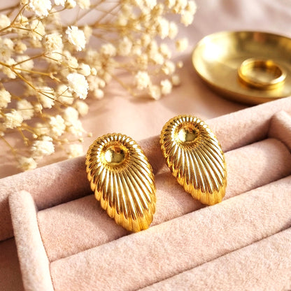 Aesthetic lifestyle shot of the gold shell earrings nestled in a pink velvet jewelry box with dried flowers.