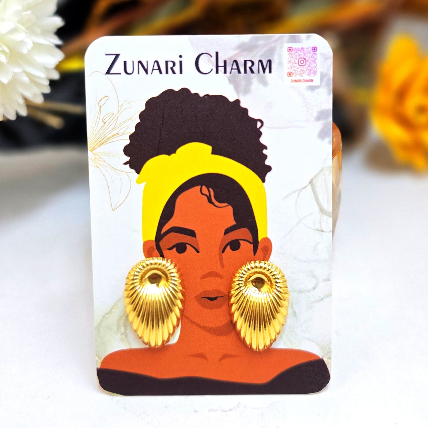 Gold shell studs presented on a Zunari Charm branded card featuring an illustrated woman with a yellow turban.