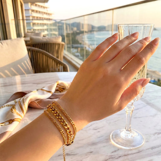 Woman wearing a 3-layer gold bracelet featuring mixed chain textures (curb, flat, and beaded).