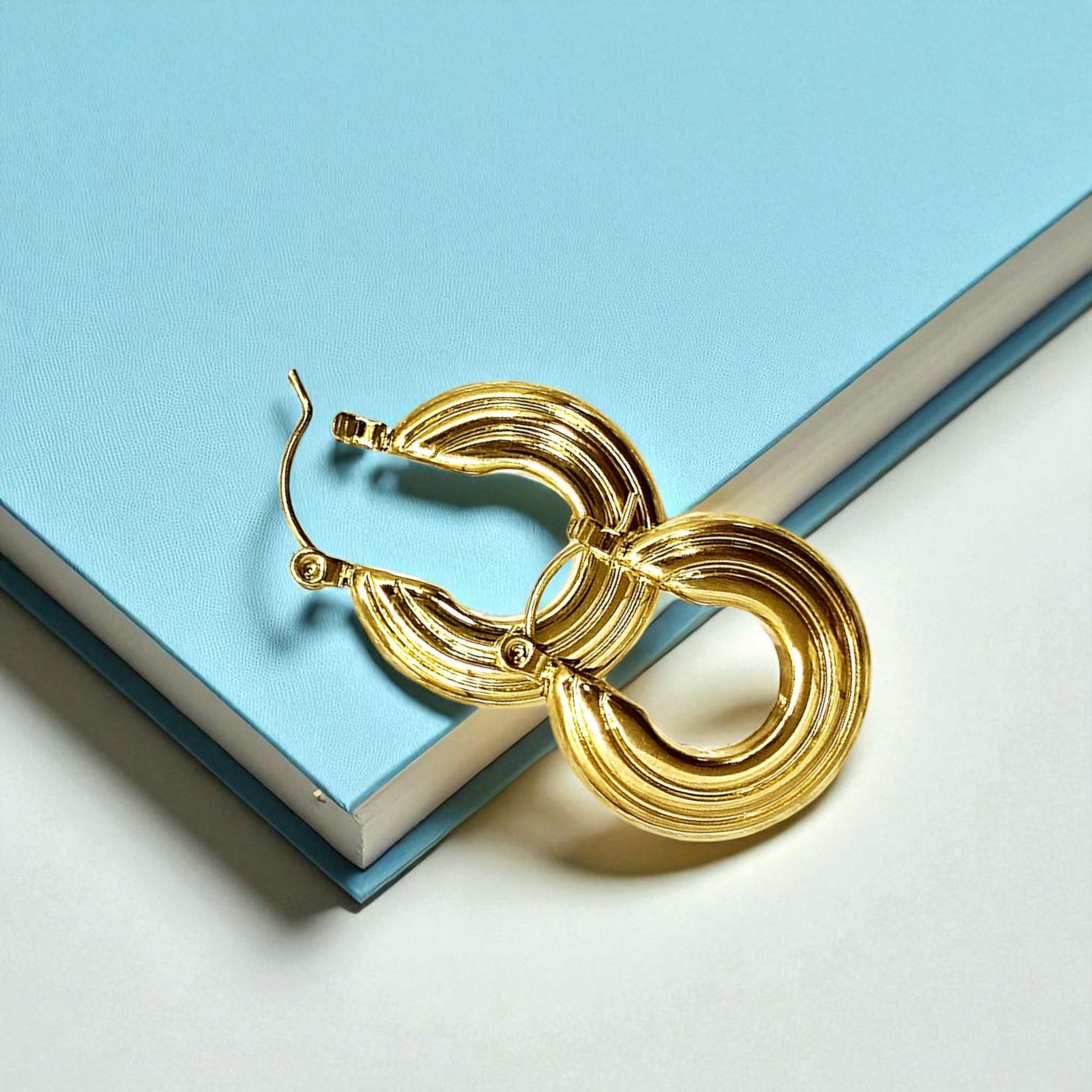 Groovy Earrings – gold textured hoop earrings displayed on blue book