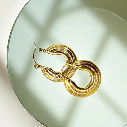Groovy Earrings – gold hoops with textured design on a green plate