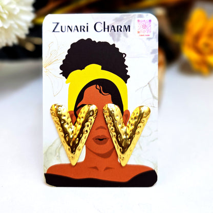 Hammered gold V-shaped earrings presented on a Zunari Charm branded card with an illustrated woman in a yellow turban.