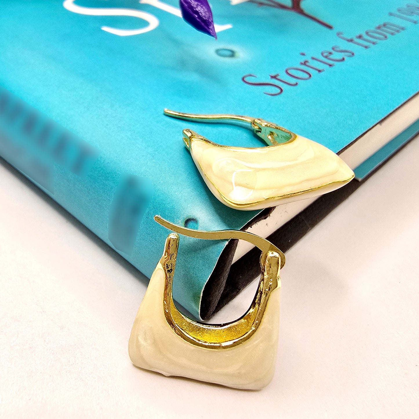 Handbag Earrings – chic ivory gold earrings placed on a blue book