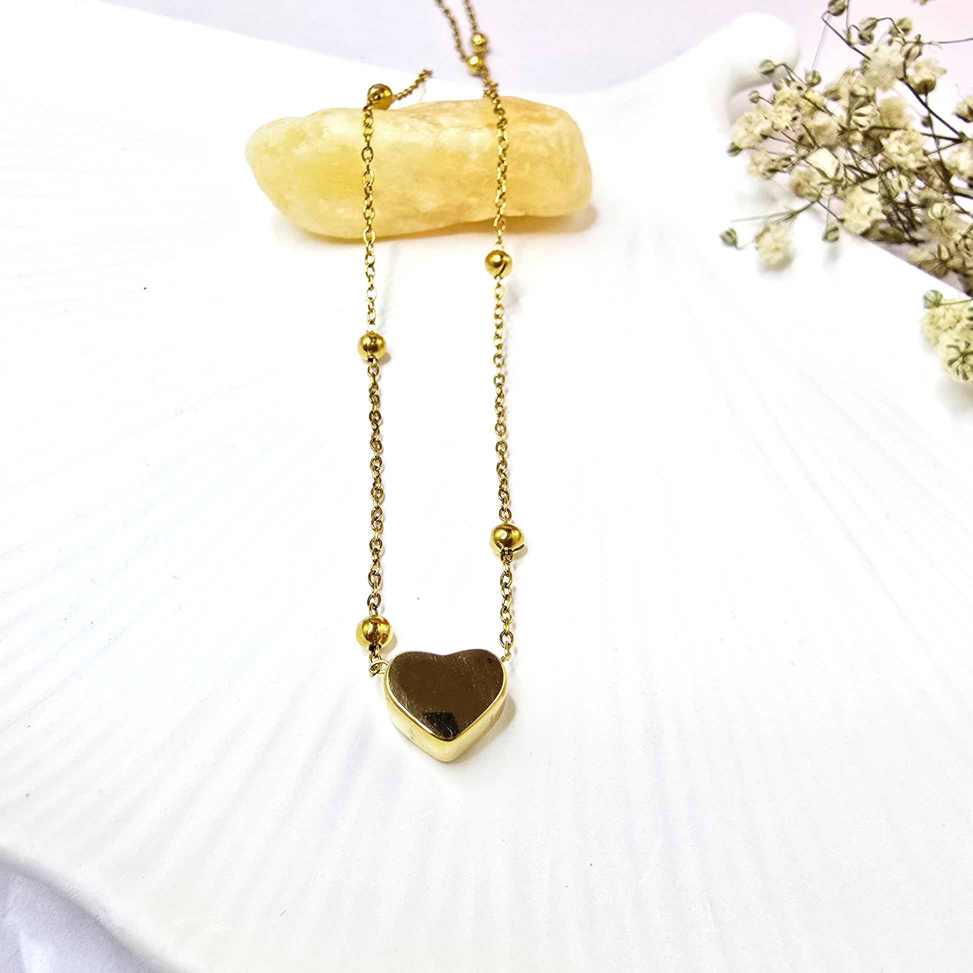 Close-up of Heart Bead Necklace on white shell background showing smooth finish.